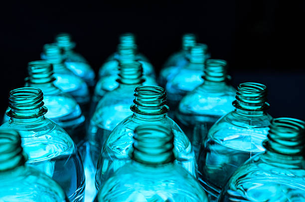 Long row of plastic blue  bottles on black background, studio shot.