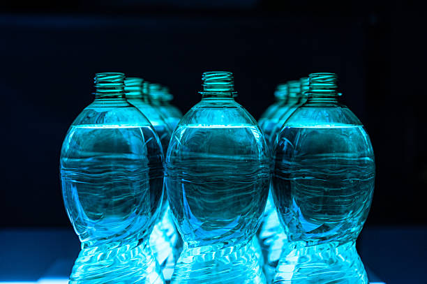 istock Long row of plastic  blue bottles on black background 2242196663