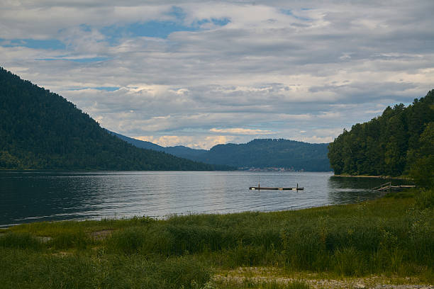 Altai mountains, and lake Teletskoe (Altyn Kohl). Beautiful calm nature landscape image with a blue sky at summer. The fields of grass, hills, rivers and mountains. Simple view, natural colors. Made in June