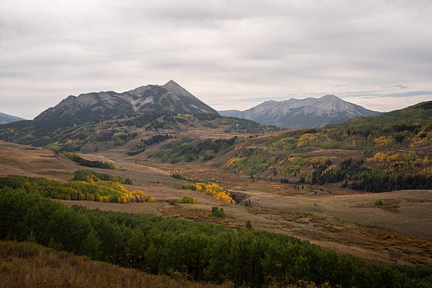 Aspen groves in fall colors dot a Colorado landscape beneath Mount Crested Butte, seen from Gothic Basin