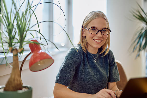 istock Young woman smiling while working on laptop in office 2242197115