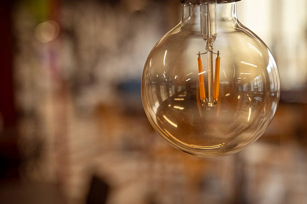 istock A classic designed tungsten lightbulb is glowing in orange warmlight shade with blurred background 2242197372