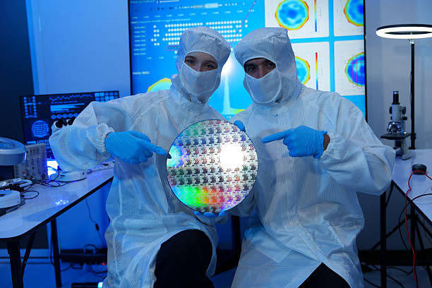 istock Engineers in sterile suits work at a semiconductor manufacturing plant using microscopes in a lab. 2242198386