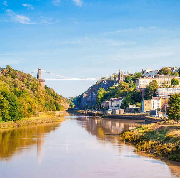 A sunny morning at high tide, with a view of the Clifton Suspension Bridge over the River Avon in Bristol, England.