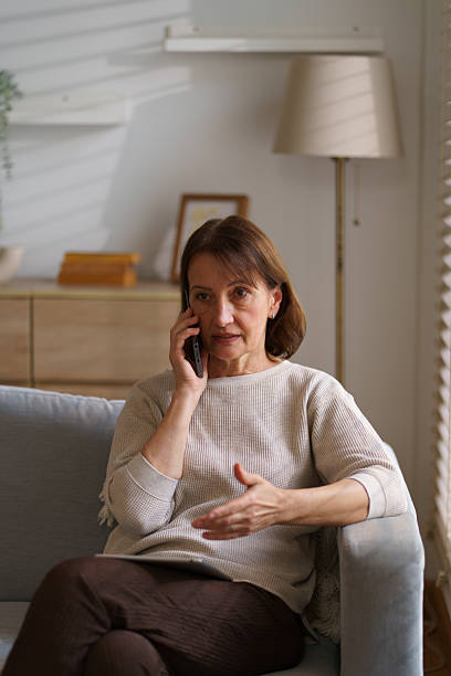 istock A woman sits on a sofa at the window in the morning, with light reflecting off her face 2242201480