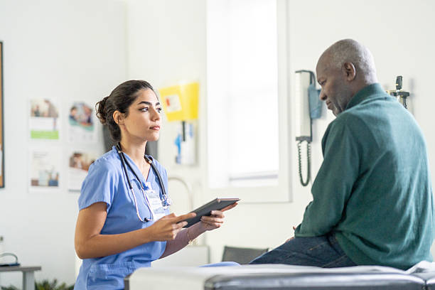 istock Compassionate Female Nurse In Scrubs Uses Tablet While Speaking With Elder Black Patient In Clinic 2242208995