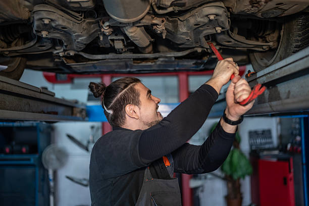 istock Mechanic Under Car On Lift Performs Repair With Tools In Auto Workshop 2242210296