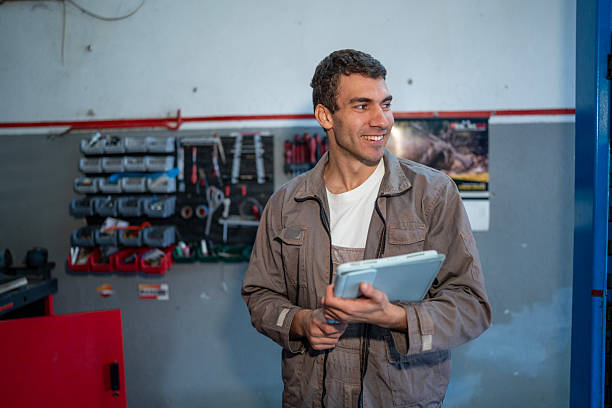 istock Smiling Technician in a Busy Workshop Holding a Tablet and Tools, Ready for Maintenance Tasks 2242210359