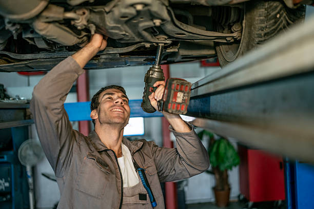istock Mechanic Under Car Lift Using Drill To Tighten Underbody Components At Auto Shop 2242210532