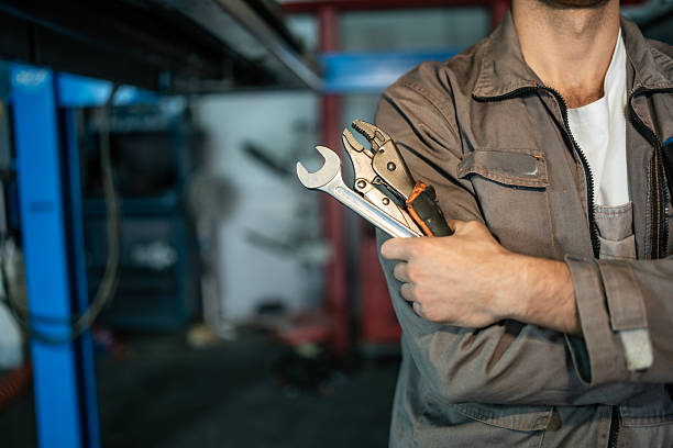 istock Professional Worker in Workwear Holds Wrenches and Tools in a Busy Workshop Setting 2242210604