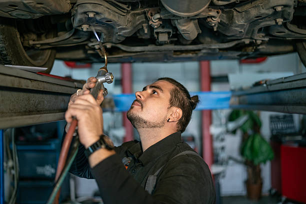 istock Skilled Mechanic Under Vehicle Using Torch For Auto Repair In A Busy Workshop 2242210674