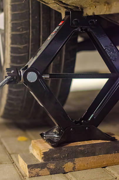 istock Car Lifted with Scissor Jack During Tire Replacement on Wooden Support Blocks 2242215268