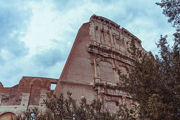 Majestic view of the Colosseum in Rome, Italy, captured from a low angle against a moody sky. The ancient amphitheater stands as an enduring symbol of Roman architecture, history, and grandeur.