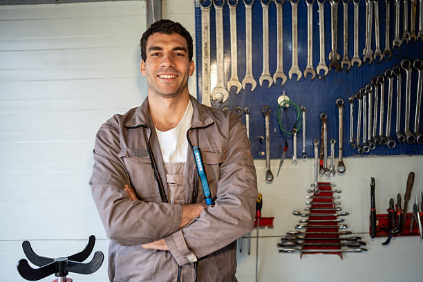 istock Confident Mechanic Stands With Arms Crossed In Workshop Surrounded By Wrenches And Tools 2242224020