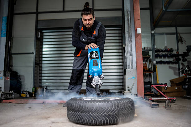 istock Workshop Worker Demonstrates Tire Demolition Using Pneumatic Tool in Auto Repair Shop During Maintenance 2242224066