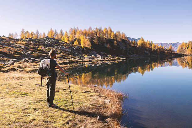 istock Man Hiking Alone by Mountain Lake Reflection 2242229997