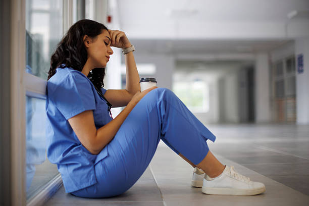 istock Exhausted nurse sitting on the hospital floor after a long shift 2242235315