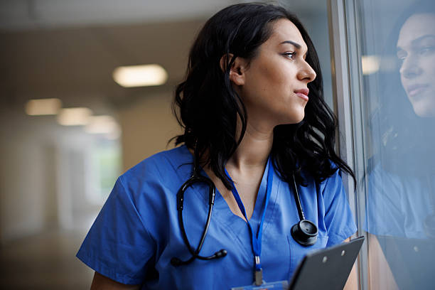 istock Thoughtful healthcare worker standing by window 2242235403
