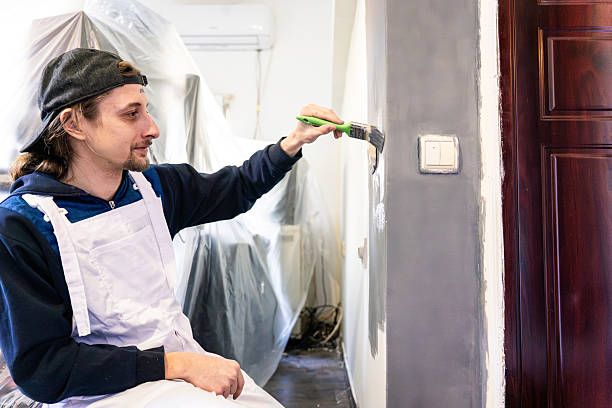 istock Painter in White Overalls Painting Wall With Green Brush During Home Renovation Project 2242236442