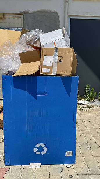 istock A blue recycling bin filled with cardboard boxes and plastic waste. 2242236700