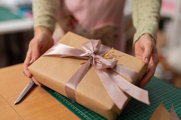 istock Woman's hands giving handmade gift box with pink ribbon 2242237127