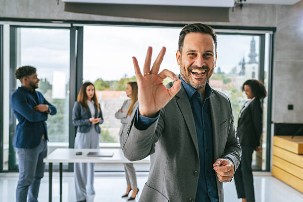 istock Confident businessman showing okay gesture happy at office 2242239404