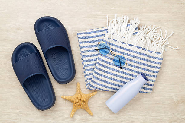 istock Beach towel with summer accessories on wooden background, top view 2242245564