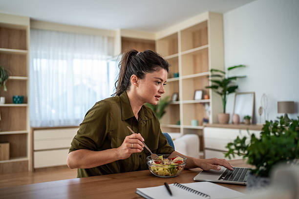 istock Woman eating a healthy salad while working remotely at home 2242246297