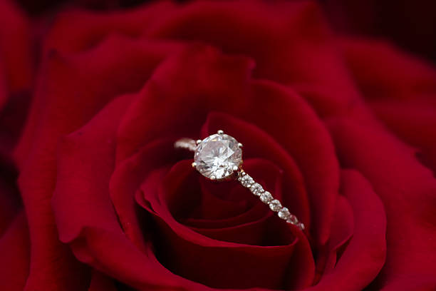 istock Elegant diamond ring resting on a lush red rose petal during a romantic setting 2242250167