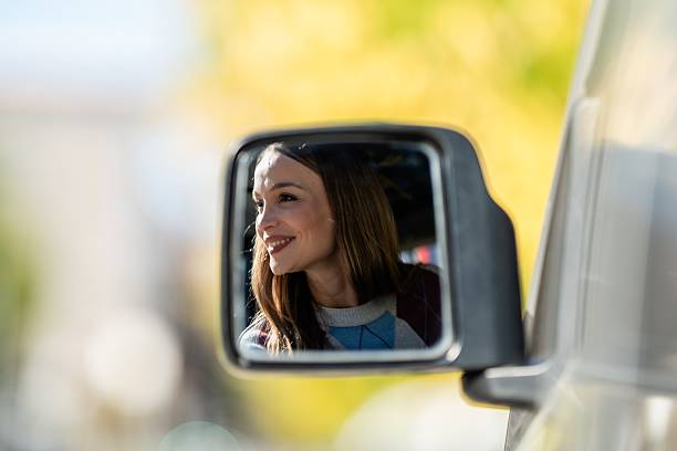 istock Woman smiling seeing reflection in car mirror 2242260456