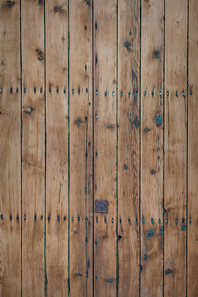 A weathered surface made with vertical wood slats and nails.