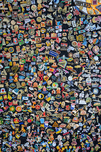 A black surface covered in colorful, faded, vintage enamel pins.