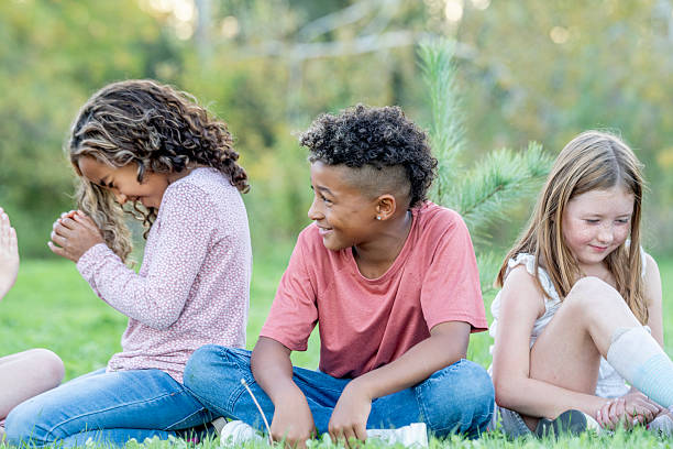 istock Friends Sitting On Grass Together: Multicultural Kids Laughing Outdoors At Park 2242270259