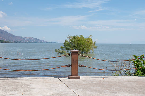 Scenic lakefront view from Jocotepec boardwalk with railing and isolated tree