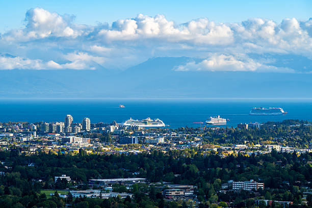 Victoria, British Columbia, Canada - May 3, 2025: Telephoto image of the busy Victoria Inner Harbour and Victoria downtown with cruise ships and the Strait of Juan de Fuca in the background.