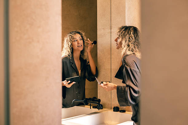 istock Young woman doing makeup at bathroom mirror, natural beauty routine in cozy home interior 2242271401