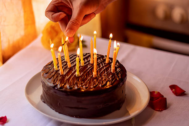 Man's hand lighting candles on chocolate birthday cake.Celebration and special event concept for party invitation or greeting card.