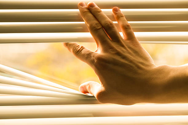 istock Man separating slats of white blinds indoors, closeup 2242282351