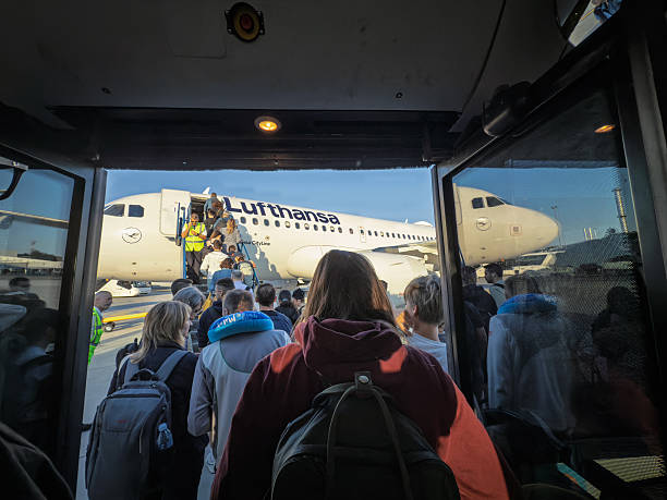 Belgrade, Serbia - June 21, 2025: Travelers crowd toward a Lufthansa jet at Belgrade Nikola Tesla Airport after arriving by apron bus, forming a queue at the mobile stairs while ground staff supervise. The frame shows airline branding, ramp operations and the bustle of gateless boarding common at European airports. Useful for coverage of aviation, airline customer experience, hub connectivity, tourism flows and operational logistics. The image fits stories about German carrier routes, seasonal demand, budget-friendly travel and the choreography of ground handling.