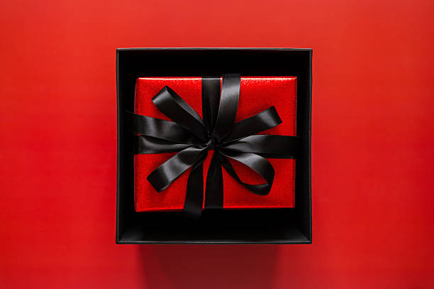 istock Black Friday concept with an open black box reveals a red gift with a black ribbon on a red background 2242287131