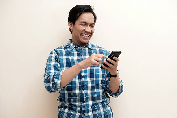 istock Southeast Asian man wearing flannel shirt standing and smiling with using mobile phone 2242289708