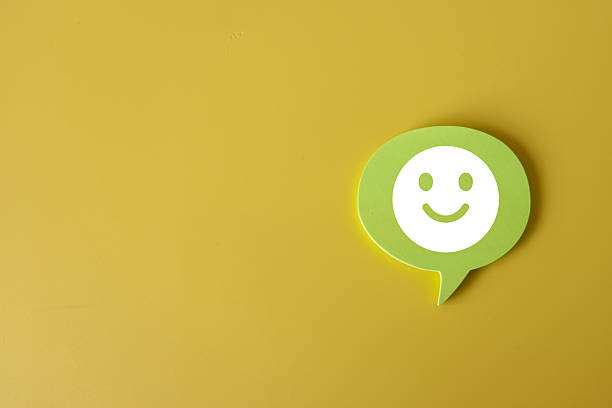 Positive concept with a green speech bubble and a smiling face icon on a bright yellow background, symbolizing happiness, optimism, and joy in a simple and modern design.