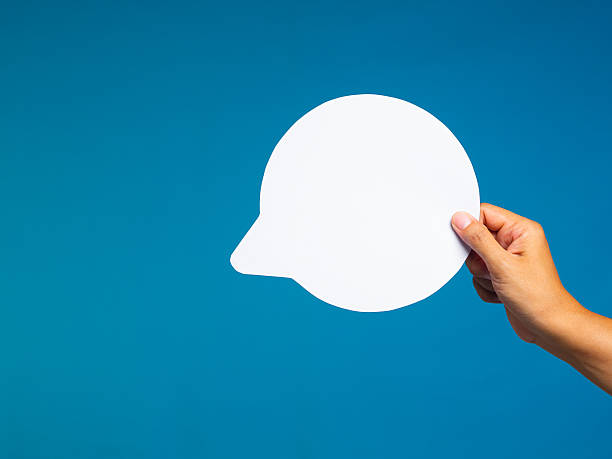 istock Person hand holding empty speech bubble cutout on blue background. 2242295154