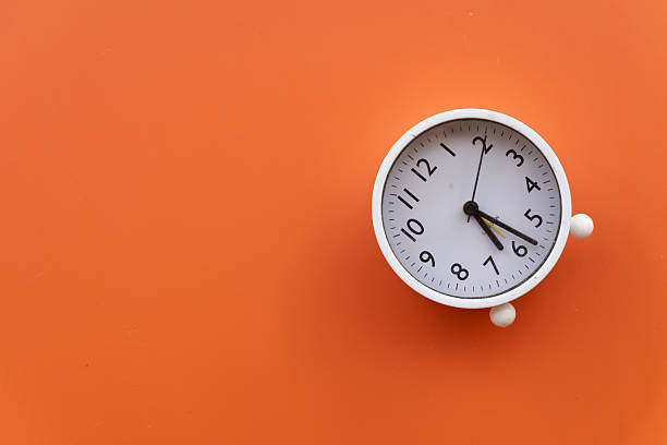 istock Time Concept: White Alarm Clock on Orange Background with Copy Space 2242307897