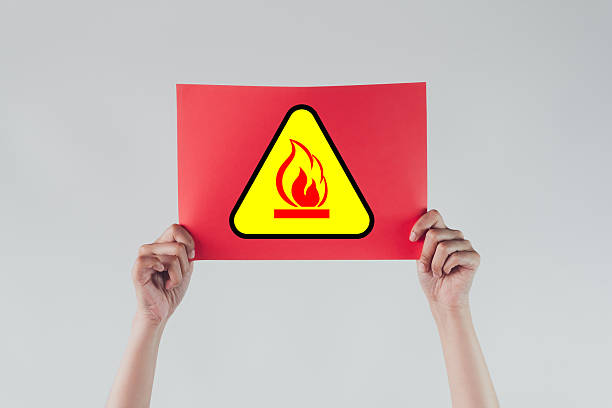 Fire Hazard Warning,Caution Flammable,Fire Risk,Flammable Sign Alert concept.,and Holding Red Paper with Flammable Sign Representing Danger, Safety Precaution, and Risk of Fire for Industrial and Workplace Safety Awareness.