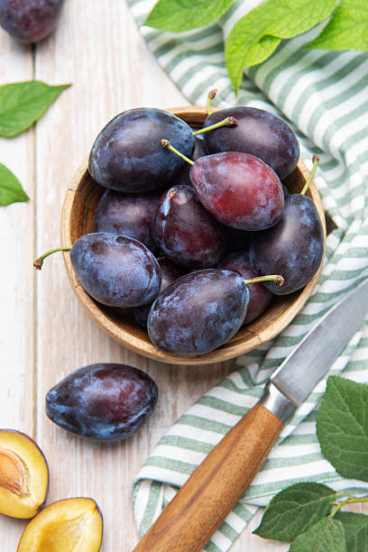 istock Fresh plums in wooden bowl with knife 2242309542