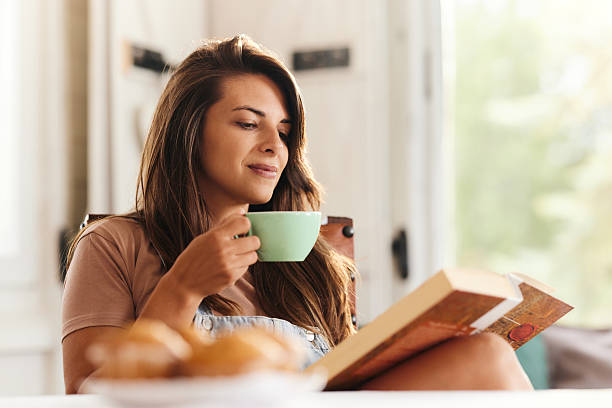 istock Smiling woman reading a book during coffee time at home. 2242316544