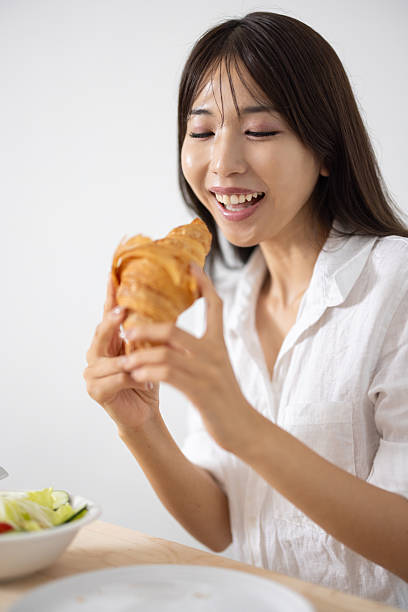 Smiling Young Woman Enjoying a Croissant for Breakfast
