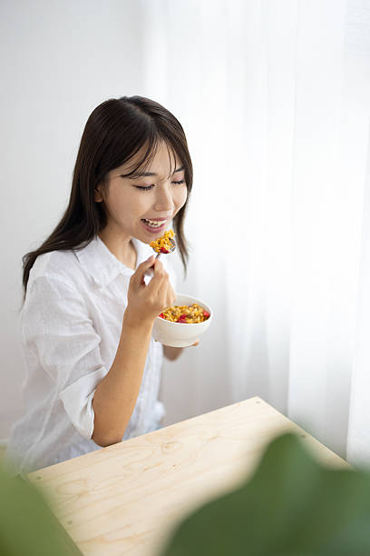 Young Woman Eating Cereal by the Window in Morning Light