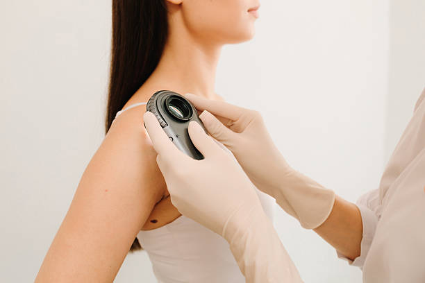 istock Dermatoscopic analysis aids in the detection of suspicious skin spots using dermatoscope during a clinical exam. Dermatologist Examining Patient Shoulder with Dermatoscope. 2242319424